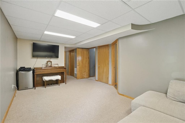 living area featuring a drop ceiling, carpet floors, and baseboards