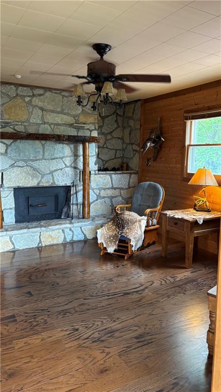 living room featuring ceiling fan, wood finished floors, and wooden walls