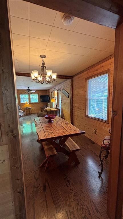 dining area featuring wood finished floors, wood walls, and a chandelier