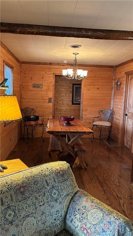 dining room with wood finished floors, a chandelier, and wooden walls