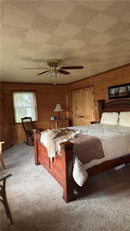 bedroom with carpet, wood walls, and a ceiling fan