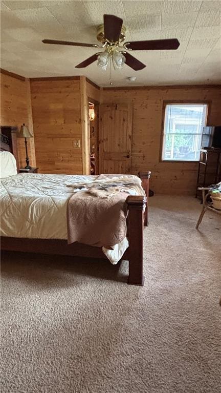 carpeted bedroom featuring wooden walls and a ceiling fan