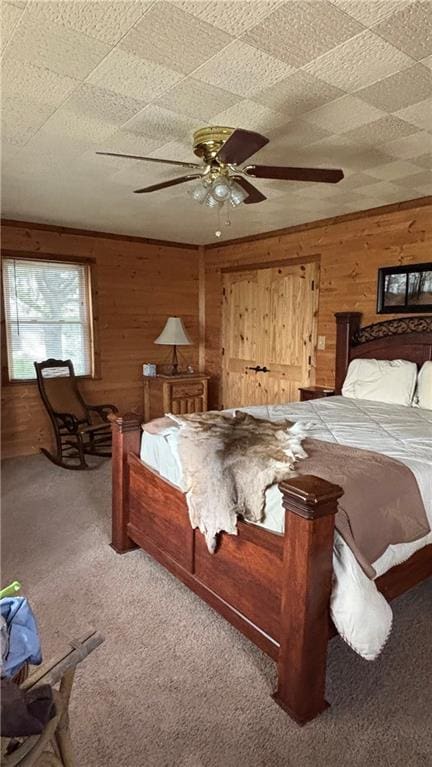 bedroom with carpet floors, wood walls, and a ceiling fan