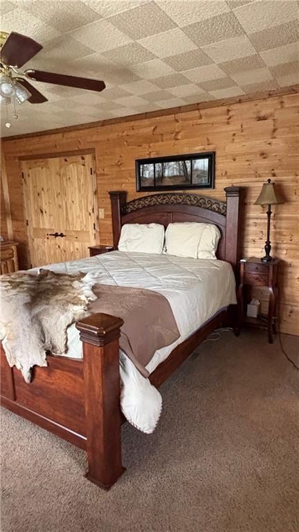 carpeted bedroom with wooden walls and ceiling fan