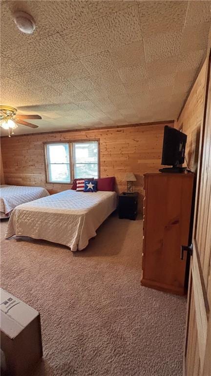 bedroom featuring carpet floors, wooden walls, and a ceiling fan