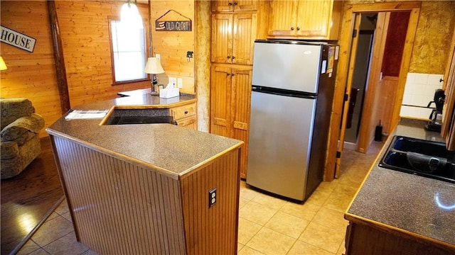 25996 Arrowhead Rd, Hermitage, MO 65668 - kitchen featuring freestanding refrigerator, wooden walls, light tile patterned floors, a peninsula, and dark countertops