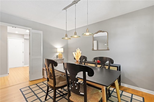 dining area with wood finished floors, baseboards, and a textured ceiling