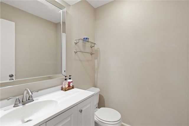 bathroom with toilet, vanity, and baseboards