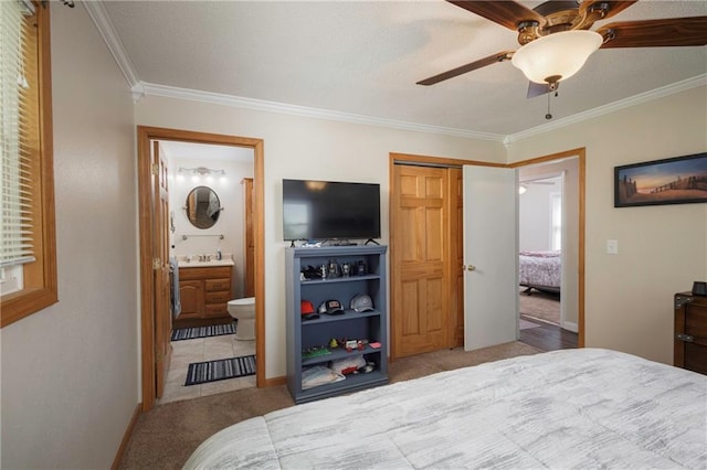 carpeted bedroom featuring crown molding, baseboards, connected bathroom, and ceiling fan