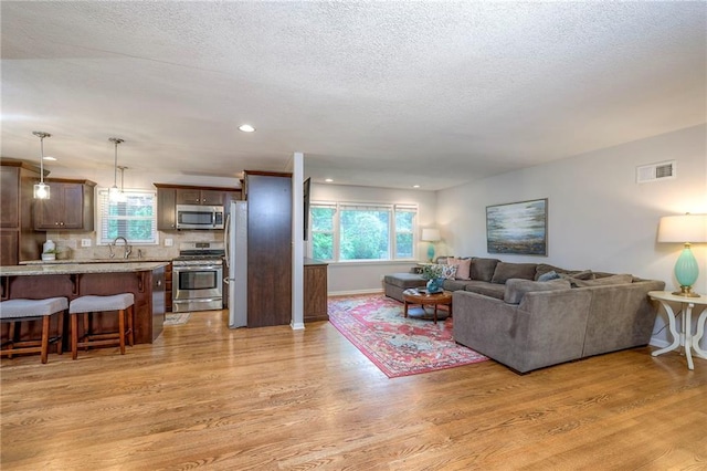 9711 Roe Ave, Overland Park, KS 66207 - living room with light wood-style flooring, a textured ceiling, and recessed lighting