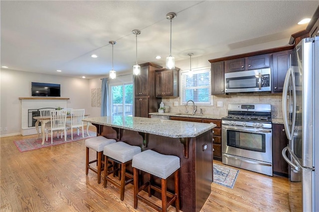 9711 Roe Ave, Overland Park, KS 66207 - kitchen featuring appliances with stainless steel finishes, light wood-style flooring, a kitchen island, a breakfast bar, and recessed lighting