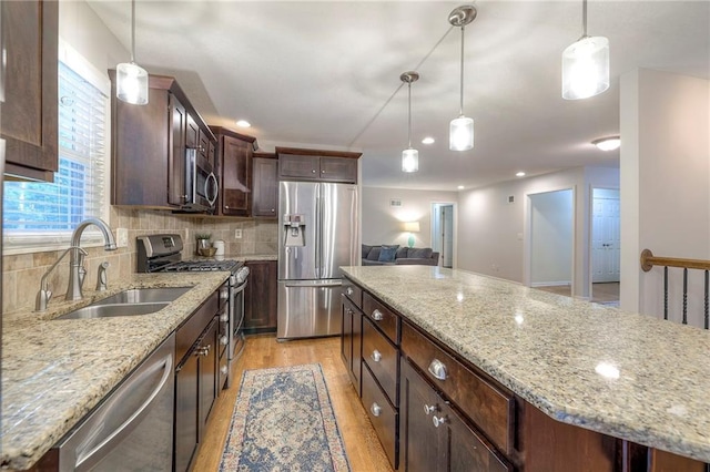 9711 Roe Ave, Overland Park, KS 66207 - kitchen featuring appliances with stainless steel finishes, light wood finished floors, dark brown cabinetry, backsplash, and hanging light fixtures