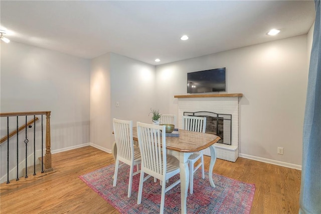 9711 Roe Ave, Overland Park, KS 66207 - dining room featuring wood finished floors, a brick fireplace, recessed lighting, and stairway