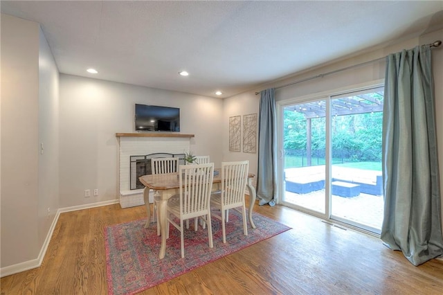 9711 Roe Ave, Overland Park, KS 66207 - dining area featuring wood finished floors, a brick fireplace, and recessed lighting