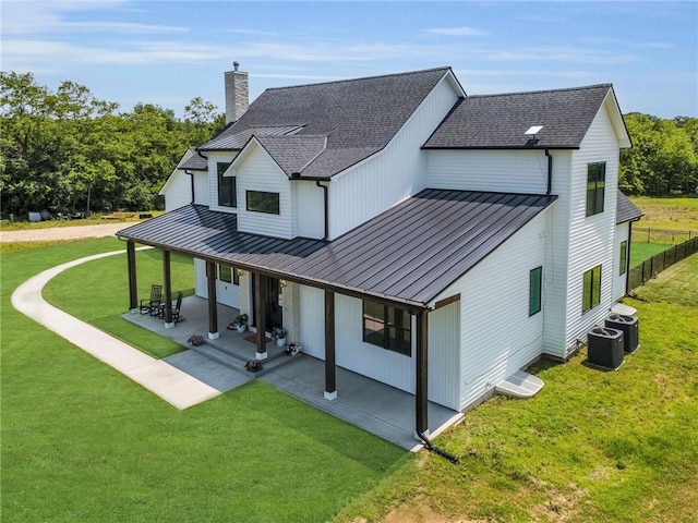 21851 179th St, Tonganoxie, KS 66086 - back of house featuring a standing seam roof, a chimney, a shingled roof, a metal roof, and a patio