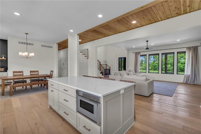 21851 179th St, Tonganoxie, KS 66086 - kitchen with a ceiling fan, a chandelier, light wood-style floors, a kitchen island, and white cabinetry