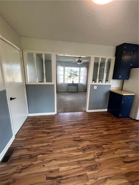 1424 S Olive St, Ottawa, KS 66067 - kitchen featuring dark wood-style flooring, a textured ceiling, blue cabinets, a ceiling fan, and light countertops