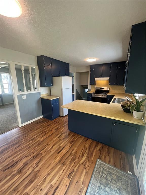 1424 S Olive St, Ottawa, KS 66067 - kitchen with electric range, a peninsula, freestanding refrigerator, dark wood-type flooring, and a textured ceiling