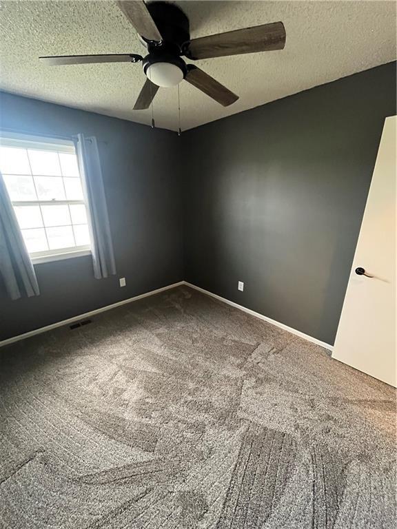 1424 S Olive St, Ottawa, KS 66067 - unfurnished room with carpet flooring, a ceiling fan, and a textured ceiling