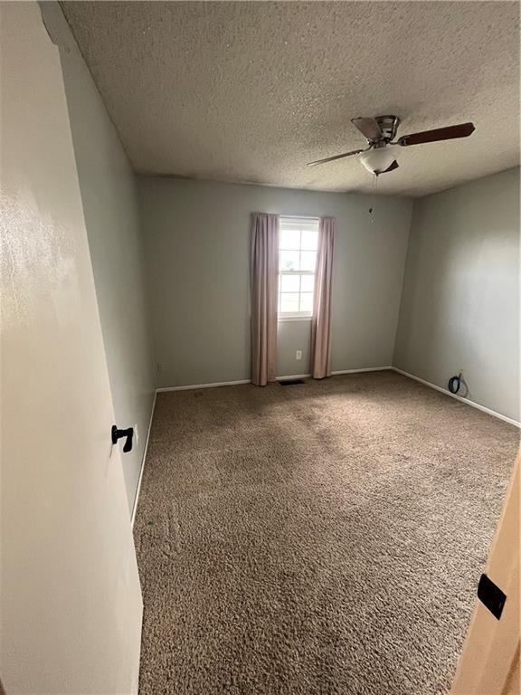1424 S Olive St, Ottawa, KS 66067 - carpeted empty room featuring a ceiling fan and a textured ceiling