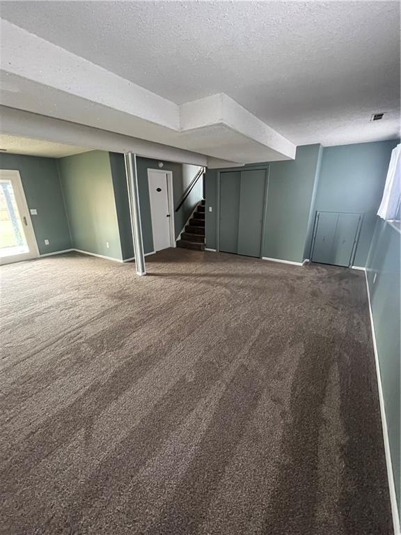 1424 S Olive St, Ottawa, KS 66067 - below grade area featuring a textured ceiling, carpet, and stairway