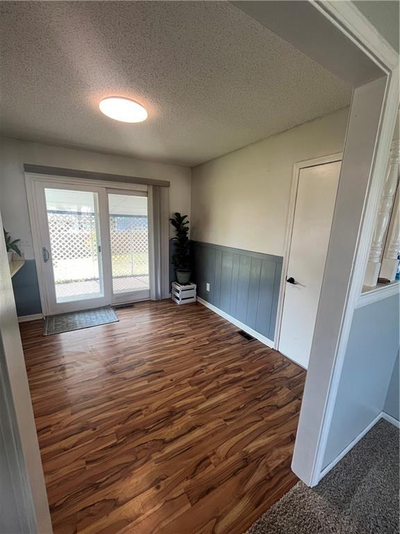 1424 S Olive St, Ottawa, KS 66067 - unfurnished room featuring wood finished floors, a textured ceiling, and wainscoting