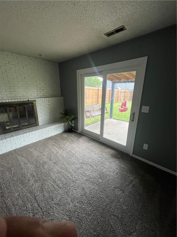 1424 S Olive St, Ottawa, KS 66067 - unfurnished living room with carpet, a textured ceiling, and a brick fireplace