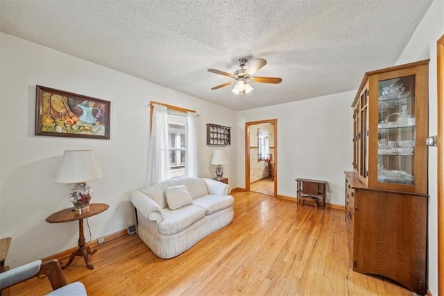 1212 E 22nd Ave, North Kansas City, MO 64116 - living area featuring light wood finished floors, ceiling fan, baseboards, and a textured ceiling
