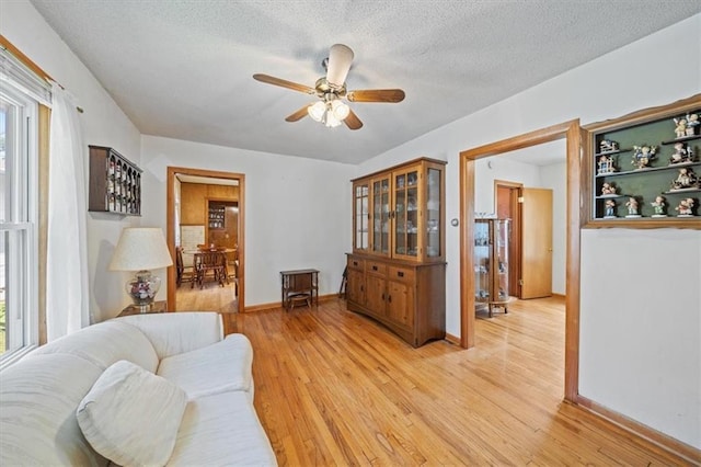 1212 E 22nd Ave, North Kansas City, MO 64116 - living room featuring a ceiling fan, light wood-style flooring, a textured ceiling, and baseboards