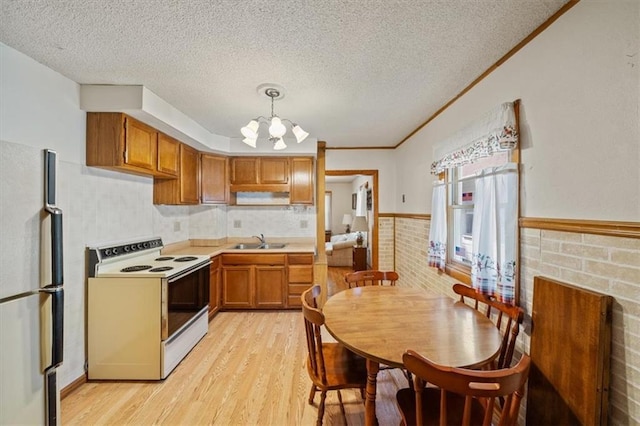 1212 E 22nd Ave, North Kansas City, MO 64116 - kitchen with white appliances, a sink, light wood finished floors, a chandelier, and brown cabinetry