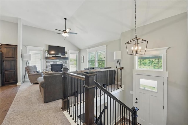 19553 E 14th St N, Independence, MO 64056 - living room featuring vaulted ceiling, wood finished floors, a stone fireplace, a chandelier, and a ceiling fan