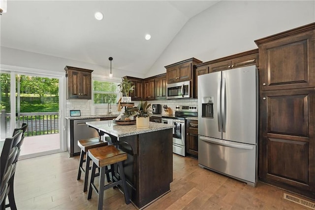 19553 E 14th St N, Independence, MO 64056 - kitchen featuring appliances with stainless steel finishes, lofted ceiling, decorative backsplash, dark brown cabinets, and a center island