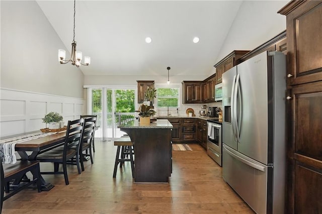 19553 E 14th St N, Independence, MO 64056 - kitchen featuring stainless steel appliances, a kitchen island, dark brown cabinets, high vaulted ceiling, and light stone counters
