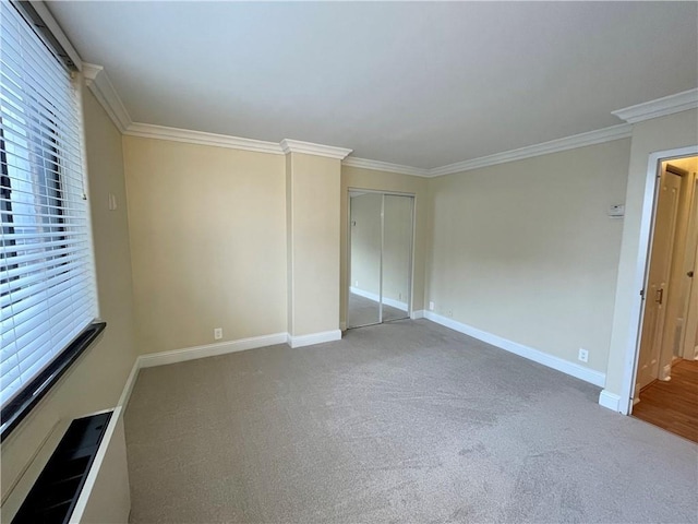 700 E 8th St Unit 10J, Kansas City, MO 64106 - unfurnished bedroom featuring multiple windows, crown molding, baseboards, carpet, and a closet