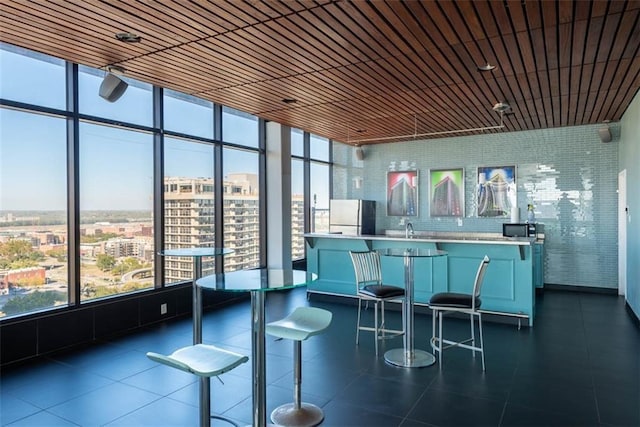 700 E 8th St Unit 10J, Kansas City, MO 64106 - kitchen featuring freestanding refrigerator, a sink, a breakfast bar, and a wall of windows
