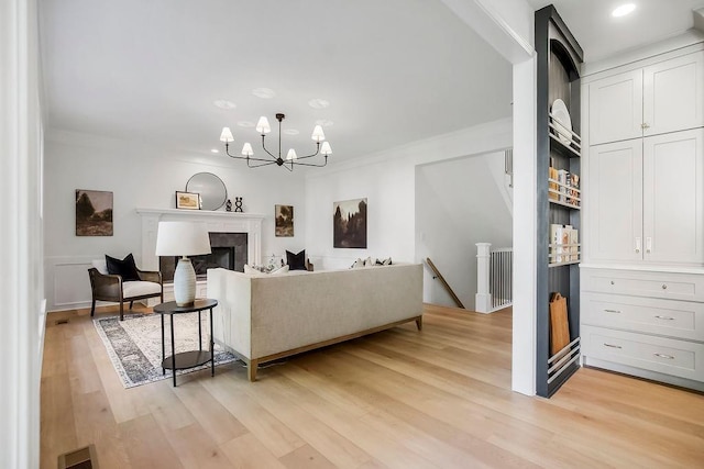living area featuring light wood-style flooring, a chandelier, ornamental molding, and recessed lighting