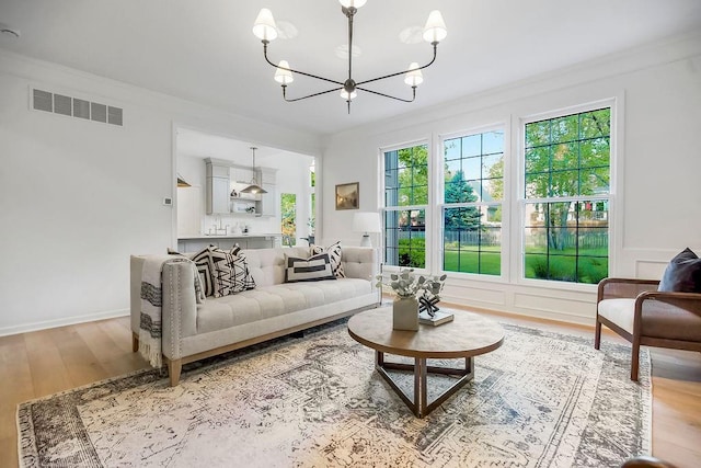 living room with wood finished floors, a chandelier, and ornamental molding