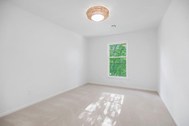 spare room featuring light carpet and baseboards