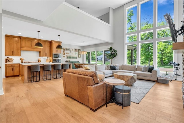 living room with light wood finished floors, a towering ceiling, and recessed lighting