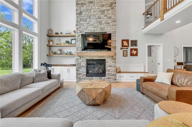 living area featuring a high ceiling, a fireplace, and light wood finished floors