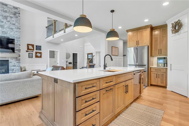 kitchen with a sink, stainless steel dishwasher, open floor plan, light wood-type flooring, and recessed lighting