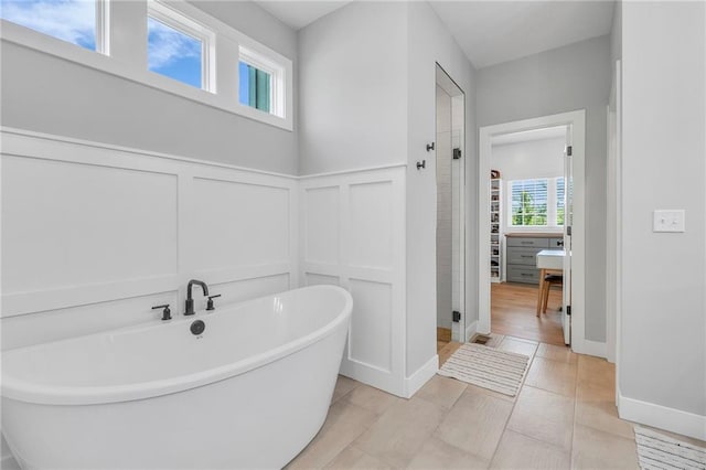 full bathroom with a decorative wall, a soaking tub, a wainscoted wall, and a stall shower