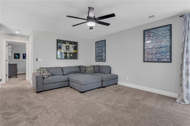 carpeted living area with ceiling fan and baseboards