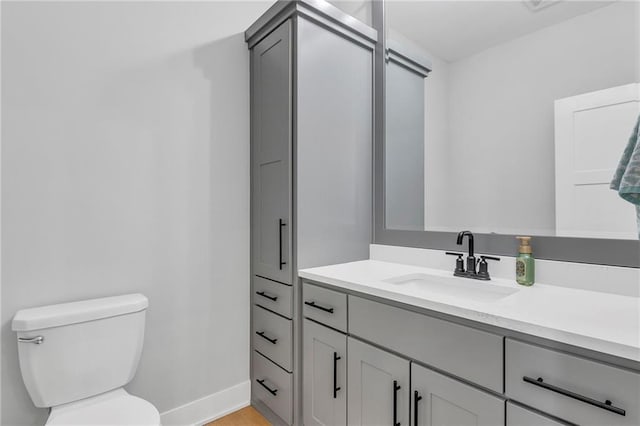 bathroom featuring toilet, baseboards, and vanity