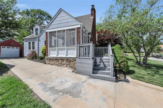 7126 Charlotte St, Kansas City, MO 64131 - view of front of property with an outdoor structure, a detached garage, concrete driveway, a chimney, and a shingled roof