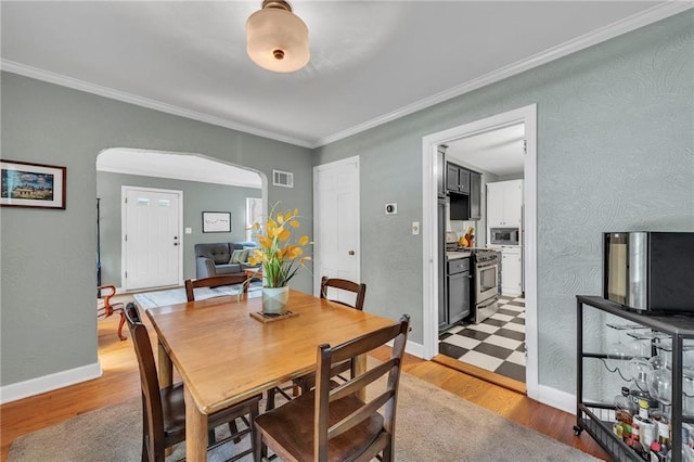 7126 Charlotte St, Kansas City, MO 64131 - dining space featuring arched walkways, crown molding, light wood-type flooring, and baseboards