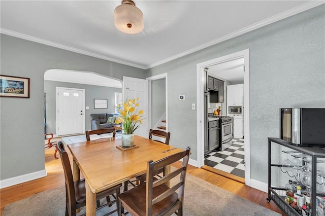 7126 Charlotte St, Kansas City, MO 64131 - dining area with arched walkways, light wood finished floors, crown molding, and baseboards