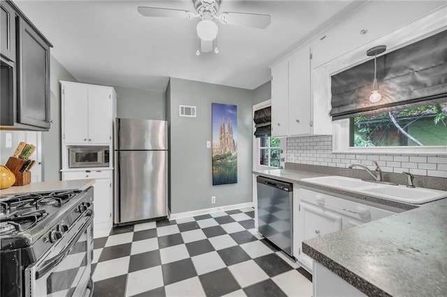 7126 Charlotte St, Kansas City, MO 64131 - kitchen with appliances with stainless steel finishes, dark floors, a sink, backsplash, and white cabinetry