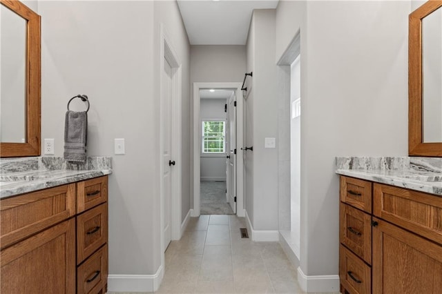 bathroom with two vanities, baseboards, and tile patterned flooring