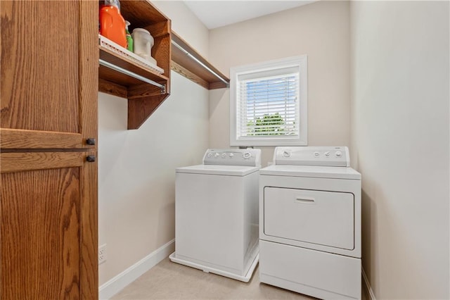 clothes washing area featuring separate washer and dryer and baseboards